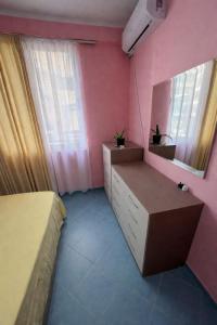 a bedroom with pink walls and a bed and a mirror at Aldi APARTMENTS in Lezhë