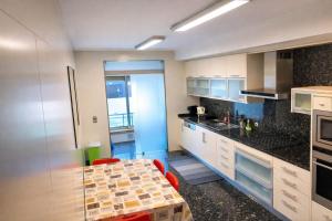 a kitchen with white cabinets and a table with red chairs at Oporto Beach Apartment in Vila Nova de Gaia