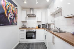 a kitchen with white cabinets and a painting of a lion at The Original Donnini Apartment in Ayr
