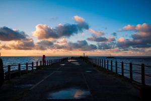 a woman standing on a pier next to the ocean at The Original Donnini Apartment in Ayr
