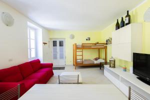 a living room with a red couch and a bed at Casa Rosa - hidden Garden with lake view in Fiumelatte