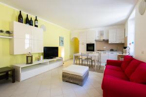 a living room with a red couch and a kitchen at Casa Rosa - hidden Garden with lake view in Fiumelatte