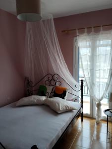 a bedroom with a bed with a canopy and a window at Kalli's View in Evdilos