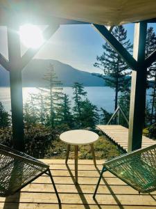 a table and chairs on a porch with a view of the water at Gorgeous Ocean and Mountain View King Suite in Bowen Island