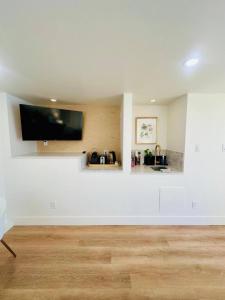 a living room with a white wall with a flat screen tv at Gorgeous Ocean and Mountain View King Suite in Bowen Island