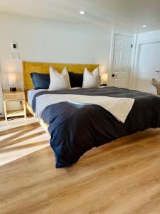 a bedroom with a large bed with blue and white pillows at Gorgeous Ocean and Mountain View King Suite in Bowen Island +4 photos