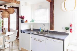 a kitchen with white cabinets and a sink and a table at Epic Apartment in Downtown Stowe in Stowe +26 photos