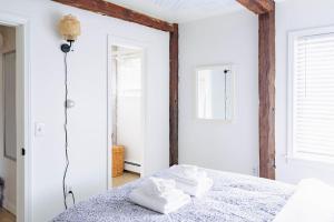 a bedroom with white walls and a bed with two towels at Epic Apartment in Downtown Stowe in Stowe