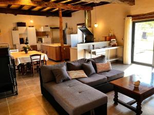 a living room with a couch and a kitchen with a table at Périgourdine avec spa et vue in Pomport