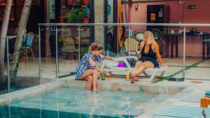 two women sitting next to a swimming pool at Viajero Cali Hostel & Salsa School in Cali +42 photos
