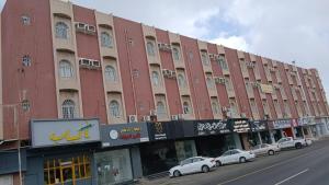 a large red building with cars parked in front of it at Golden New Alareen-جولدن العرين أبها in Abha