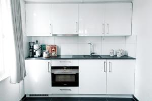 a white kitchen with white cabinets and a sink at Ferien Wohnung mit Seeblick in Romanshorn