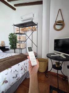 a person holding a remote control in a bedroom at Casa Rural El Refugio in Zuheros +51 photos