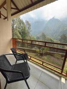 a balcony with two chairs and a view of the mountains at HLB Homestay in Ngadisari