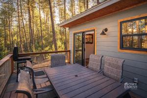 a wooden table and chairs on a deck with trees at T-Post - A Beautiful New-Build with Treetop Deck in Ruidoso