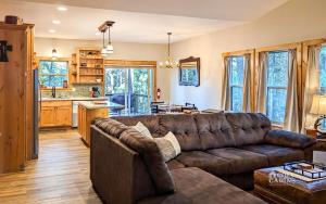a living room with a brown couch and a kitchen at T-Post - A Beautiful New-Build with Treetop Deck in Ruidoso +30 photos