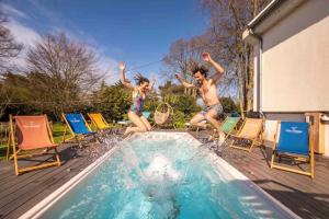 two young people jumping into a swimming pool at EDEN LOCQUIREC l Flow Breathe & SPA l La Chambre d'Hôtes réinventée in Locquirec