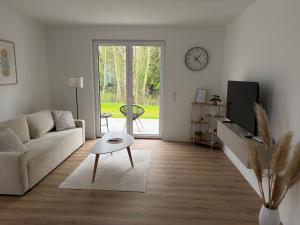 a living room with a couch and a table and a clock at Bauna Suites & Apartments in Baunatal