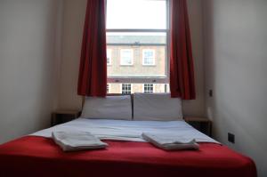 ロンドンにあるグッドウッド ホテルの窓の前にタオル2枚が付いたベッド