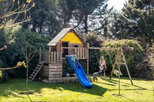 a family playing on a slide in front of a play house at EDEN LOCQUIREC l Flow Breathe & SPA l La Chambre d'Hôtes réinventée in Locquirec