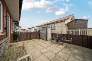 a patio with two benches and a fence at 1 Bed Cabin - Sleeps 2 - Pets - 2 Min To Beach in Bridlington