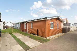 a small wooden house in a yard with a driveway at 1 Bed Cabin - Sleeps 2 - Pets - 2 Min To Beach in Bridlington