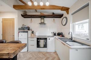 a kitchen with white appliances and a wooden table at 1 Bed Cabin - Sleeps 2 - Pets - 2 Min To Beach in Bridlington