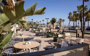 a patio with tables and chairs and palm trees at Ilunion Fuengirola in Fuengirola