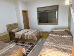 ein Zimmer mit drei Betten und einem Fenster in der Unterkunft Oak Chalet in Umm al Manābī‘