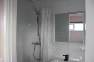 a bathroom with a shower and a sink and a mirror at Svala Guesthouses in Selfoss