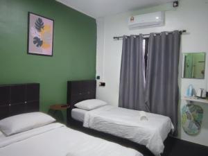 two beds in a room with green walls at Green Forest Resort in Setiu