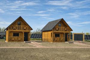two wooden barns with solar panels in a field at Noclegi Przy Karczmie in Makowiec