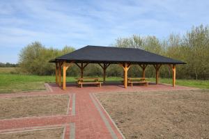 a pavilion with two benches and a black roof at Noclegi Przy Karczmie in Makowiec