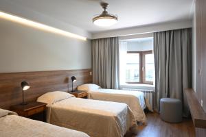 a hotel room with three beds and a window at Hotel Nevada in San Carlos de Bariloche