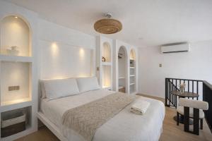 a white bedroom with a bed and a table at Villa Adela Siargao in General Luna