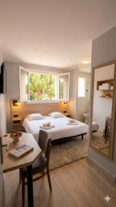 a bedroom with two beds and a table and a mirror at VTF Village de vacances Le Domaine d'Agde in Agde