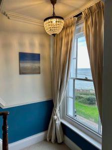 a room with a window and a chandelier at Barley House, Sea and Beach Facing Accommodation in Southwold
