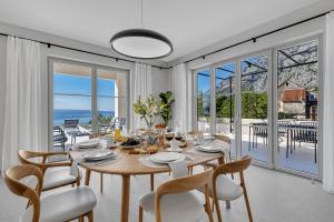 a dining room with a table and chairs and windows at Villa Laurante in Tučepi