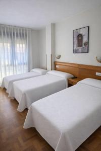 a group of four beds in a room at Pensión Mencia in Lugones