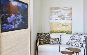 a living room with a white couch and a painting at Elefthia Syros - Luxury Houses & Suites in Megas Gialos - Nites