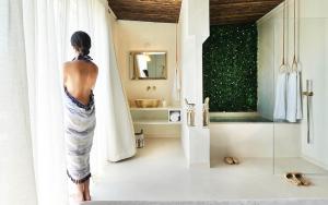a woman standing in a bathroom looking at a mirror at Elefthia Syros - Luxury Houses & Suites in Megas Gialos - Nites +43 photos