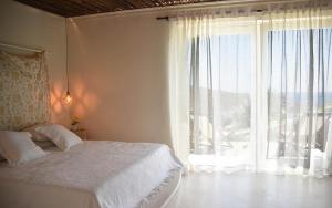 a bedroom with a bed and a large window at Elefthia Syros - Luxury Houses & Suites in Megas Gialos - Nites