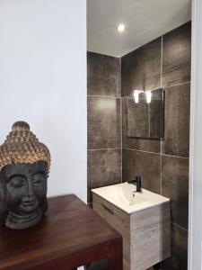 a bathroom with a sink and a mask on the wall at Les Anges de la Vigne par Lisca Begay in Biron +30 photos
