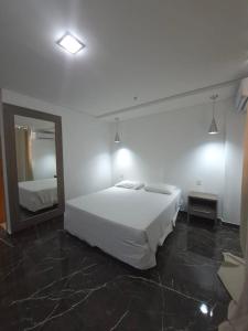 a bedroom with a white bed and a mirror at Lindo Flat Completo 311 in Nova Iguaçu
