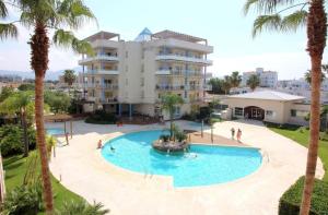 a swimming pool in front of a building with palm trees at La Casa Terracotta, ménage et linge inclus in Roses