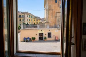 a window with two people sitting on a bench looking out at Borgo & Terrazza - Le Case di Rio in Rio nellʼElba
