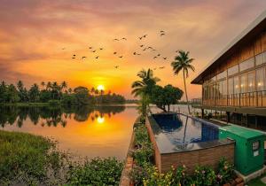 a sunset over a body of water next to a building at Kyna Backwater Resort Alleppey Alappuzha in Alleppey