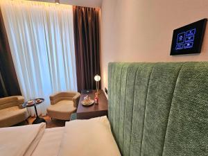 a hotel room with a green couch and a chair at Hotel Center Ljubljana in Ljubljana