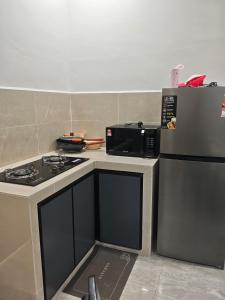 a kitchen with a stove and a microwave at Homestay Ayong in Parit Raja +2 photos