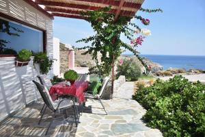 a patio with a table and chairs and the ocean at Elefthia Syros - Luxury Houses & Suites in Megas Gialos - Nites